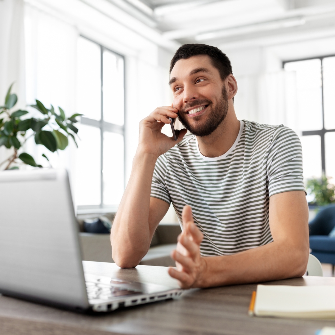 man talking on phone in front of laptop